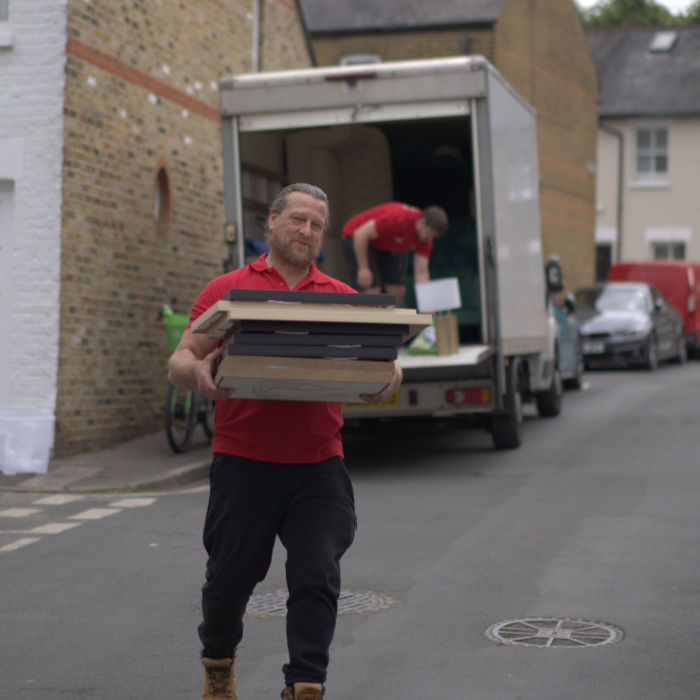 Hitchin Removals team member carrying items from a moving truck in a residential area