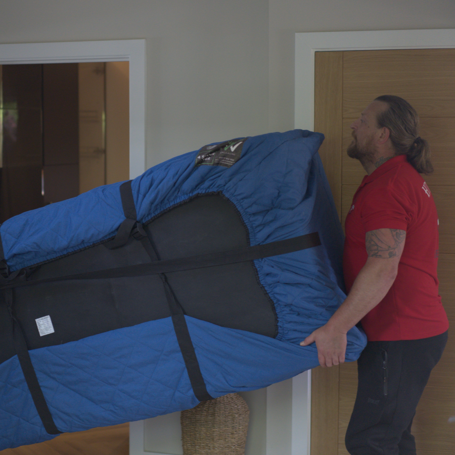 Hitchin Removals team member maneuvering a covered sofa inside a house