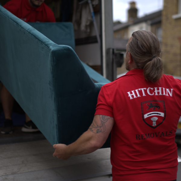 Hitchin Removals team member carrying items from a moving truck in a residential area